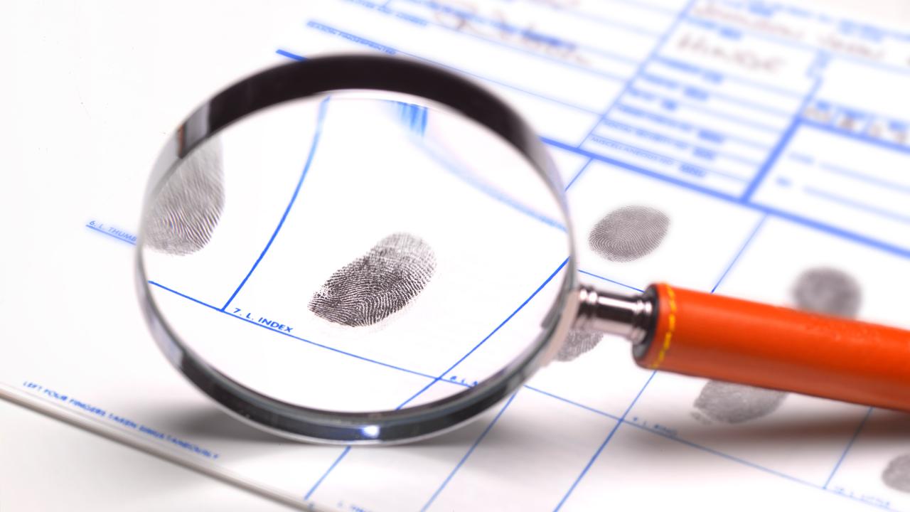 magnifying glass showing a fingerprint on a fingerprint card