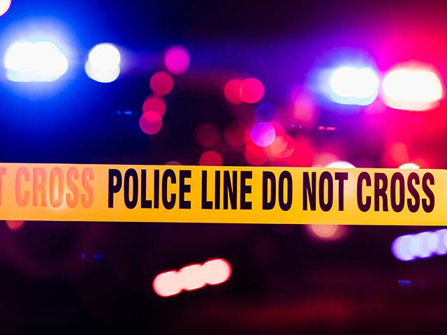 police crime scene tape in front of flashing emergency lights at night